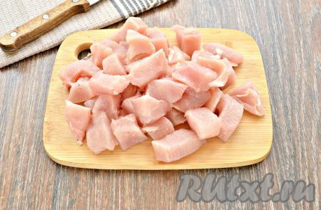 Для приготовления плова прекрасно подойдёт как куриное филе, так и мясо, срезанное с любых частей курицы. Если куриное мясо заморожено, его нужно разморозить заранее. Размороженное куриное мясо промыть под холодной водой, обтереть бумажным полотенцем. Нарезать мясо курицы на кусочки среднего размера. В чашу мультиварки к морковке, обжаренной с луком, выложить кусочки куриного мяса.