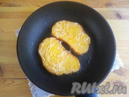 Сковороду с растительным маслом разогреть, выложить хлебные ломтики. Жарить гренки с сыром и яйцами на среднем огне около минуты (до зарумянивания). За это время яйцо «схватится», а сыр расплавится.