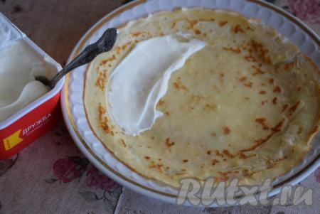 Готовые блины снимаем со сковороды и смазываем сливочным маслом. Охлаждаем наши блинчики, затем выкладываем по одному на тарелку и смазываем поверхность каждого блина плавленным (или творожным) сыром.