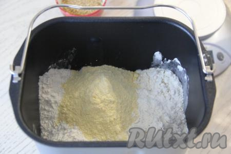 Всыпать сюда же просеянную пшеничную и кукурузную муку, добавить дрожжи, установить режим "Белый хлеб" на 3 часа 20 минут. В отсек для сухих добавок, по желанию, всыпать кунжут. Если нет отсека, то добавить кунжут по звуковому сигналу во время замеса теста. Закрыть крышку хлебопечки,