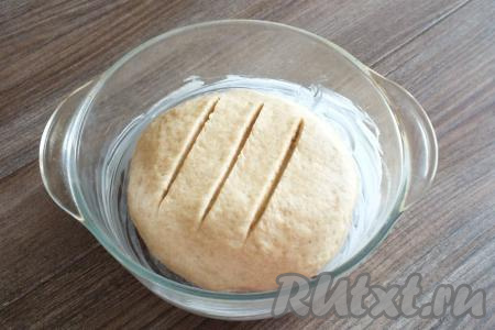 Возьмите форму для выпечки, смажьте её сливочным маслом. Из теста сформируйте шар и выложите его в форму. На поверхности шара сделайте 3 разреза острым ножом, прикройте полотенцем и оставьте в тепле на 30 минут.