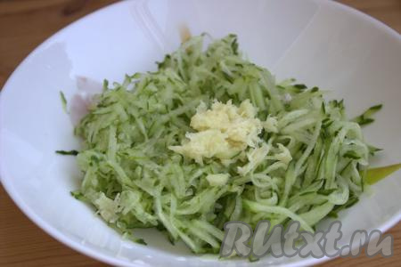 Пропустить через пресс очищенные зубчики чеснока и добавить в миску к натёртым огурцам.