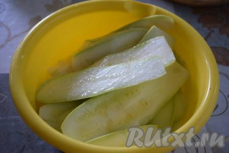 Молодые кабачки (с тонкой кожицей и мелкими семенами), не очищая от кожуры, нарезаем вдоль на пластины толщиной 4-5 мм. Складываем нарезанные кабачки в миску, посыпаем их солью и даём немного полежать. Сливаем с кабачков образовавшийся сок. Далее добавляем 0,5 столовой ложки растительного масла и руками растираем его по всей поверхности кабачков.