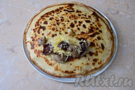 На каждый блин, ближе к краю (как на фото), выкладывайте по 1,5-2 столовые ложки начинки, затем подогните бока блина к центру на начинку и, начиная с края с начинкой, сверните блинчик рулетиком.