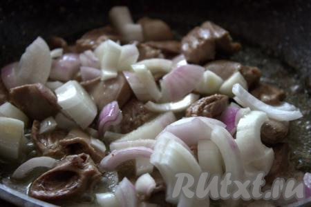 В сковороде хорошо разогреть растительное масло, затем выложить куриные сердечки, влить 100 миллилитров холодной кипячёной воды, накрыть крышкой. А после того как вода закипит, тушить сердечки на среднем огне 20 минут. Затем в сковороду к сердечкам добавить очищенный и нарезанный на четвертинки репчатый лук. Помешивая, обжаривать лук до мягкости и прозрачности (минут 5-7).