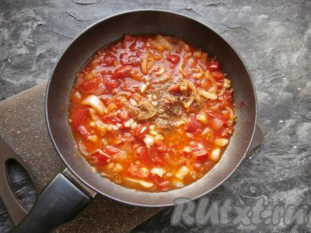 В сковороду влить горячую воду, добавить соль, специи для мяса, томатный соус, измельчённый чеснок, перемешать, дать получившемуся соусу закипеть, а затем потомить его на небольшом огне около 5 минут.