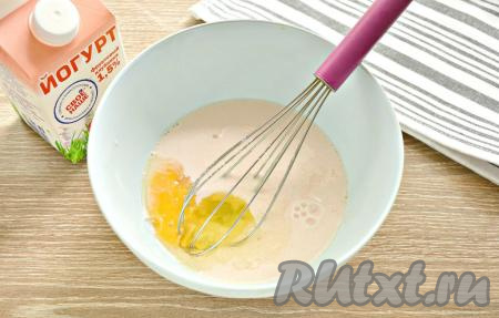 В миску вливаем питьевой йогурт, туда же вбиваем сырое куриное яйцо, всыпаем сахар и небольшую щепотку соли.