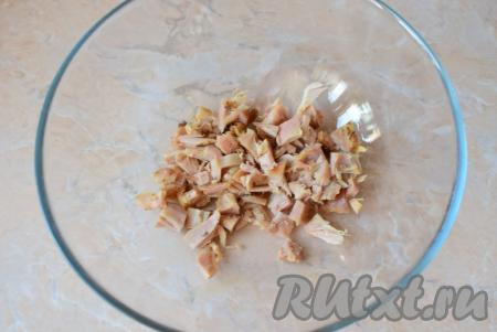 Отделите мясо от костей, нарежьте на небольшие кусочки и выложите в объёмную миску, в которой будете готовить салат.