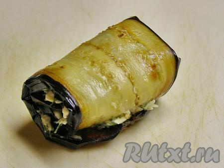 Сворачиваем пластину жареного баклажана с начинкой из сыра, укропа и чеснока в рулет. Так формируем все рулетики. Убираем приготовленные рулетики в холодильник, примерно, на 30 минут.