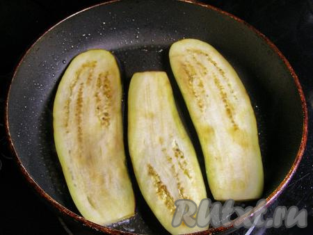 Через 10 минут ополаскиваем пластинки баклажанов прохладной водой и просушиваем на бумажном полотенце. В сковороде разогреваем растительное масло на сильном огне, уменьшаем огонь до среднего, выкладываем пластинки баклажанов и обжариваем их до золотисто-коричневого цвета с двух сторон.