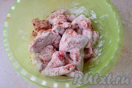 Сложите куриные крылышки в просторную чашу и засыпьте мукой с солью и специями. Перемешайте, чтобы мука, соль и специи равномерно покрыли мясо со всех сторон.