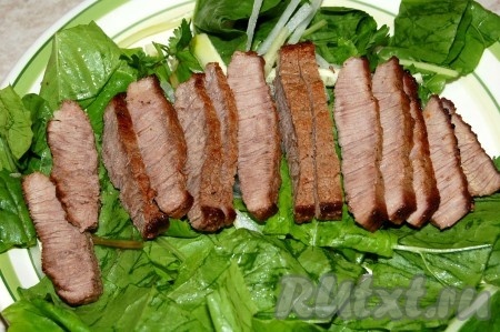 Выложить листья салата с огурцом и редисом на порционную тарелку. Сверху выложить ломтики жареной говядины.

