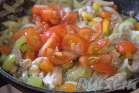 Затем в сковороду к овощам и куриному мясу добавить нарезанные на кусочки помидоры, перемешать.