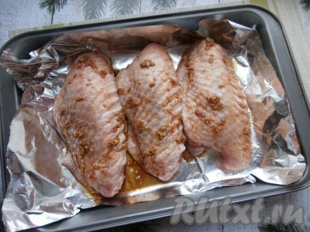 Индюшиные крылья залить подготовленным маринадом и оставить на 1-1,5 часа. Периодически крылья нужно переворачивать. Затем выложить крылья на противень, застеленный фольгой (или пергаментом).
