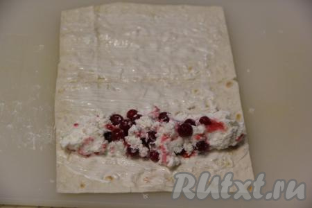 Каждую полоску лаваша смазать сметаной, оставляя края чистыми, и выложить на смазанную часть лаваша пару столовых ложек творожно-ягодной начинки.