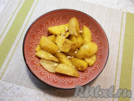 Отправить посуду с дольками картошки в микроволновку, накрыть крышкой с отверстием для выхода пара. Готовить при мощности 750 Ватт 10 минут, после чего добавить мелко нарезанный чеснок, картофель перемешать и готовить ещё 10 минут. 