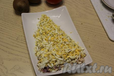 Выложить на слой курицы замаринованный и отжатый от жидкости лук. Промазать маринованный лук майонезом. Следующим слоем выложить предварительно натёртые на средней тёрке яйца.