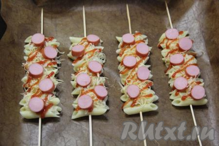 Сосиски нарезать на кружочки и выложить поверх макарон с сыром. 