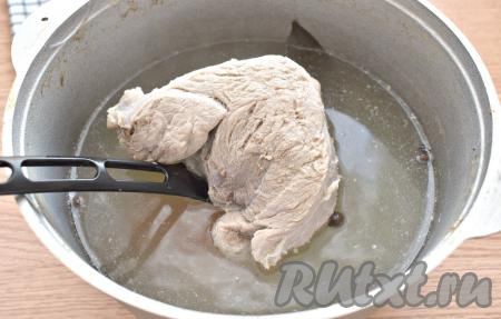 Прежде всего отварим мясо, для этого вымытую свинину кладём в кастрюлю и вливаем 1,5 литра воды, ставим на сильный огонь. После закипания воды удаляем пену, солим, уменьшаем огонь и варим 30 минут. Затем добавляем в кастрюлю целую очищенную морковку, горошины чёрного перца, целую очищенную луковицу, лавровый лист и горошинки душистого перца, продолжаем варить свинину ещё 30 минут. Готовое мясо вынимаем из бульона и оставляем до полного остывания (варёные лук и морковка нам для этого блюда в дальнейшем не понадобятся). Бульон можно использовать для варки супа.