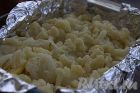 Если вы будете готовить это блюдо со свежей цветной капусты, то её нужно разделить на соцветия, промыть, поместить в кастрюлю с кипящей подсоленной водой и после закипания отварить на небольшом огне в течение 4-5 минут (капуста должна стать достаточно мягкой), откинуть на дуршлаг, чтобы убрать лишнюю воду, дать немного остыть. Я готовила с замороженной цветной капустой, уже отваренной и разобранной на соцветия, поэтому её, не размораживая, нужно было просто обдать водой и оставить на пару минут, чтобы стекла вода. Подготовленную цветную капусту выложить ровным слоем поверх сыра.