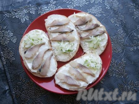 На одну половину ломтей батона выложить по 3-4 кусочка селёдки, на другую - нарезанный тоненькой соломкой свежий огурец.
