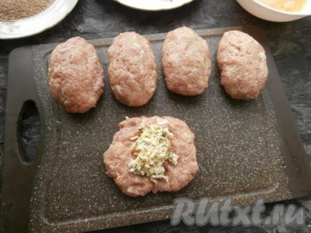 Из фарша влажными руками слепить лепёшки. В середину каждой лепёшки выложить столовую ложку начинки, а затем сформировать котлету, чтобы начинка оказалась внутри.