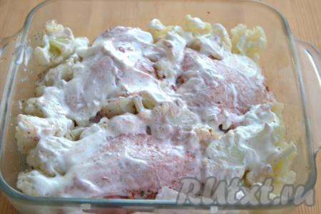 При помощи кулинарной кисти (или ложки) смазать сметаной куриные бёдра и капусту.