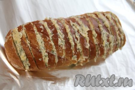 Батон, фаршированный сыром, маслом, чесноком и зеленью, переложить на кусок фольги.
