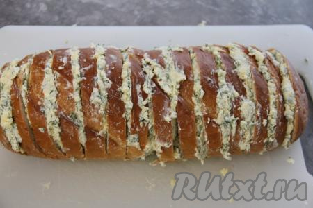 В батоне сделать глубокие надрезы, не дорезая кусочки до конца. Должна получиться "гармошка". Аккуратно выложить начинку между ломтиками хлеба.