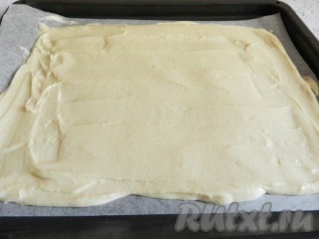 Противень застелить бумагой для выпечки, вылить тесто и распределить его равномерно по всей поверхности.