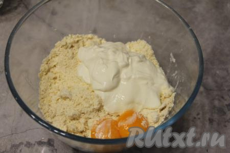 К получившейся крошке добавить яичные желтки и сметану.
