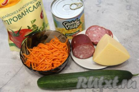 Подготовить продукты для приготовления салата с копчёной колбасой, свежим огурцом и корейской морковью. Корейскую морковку можно приобрести в магазине или на рынке, а можно приготовить и в домашних условиях.