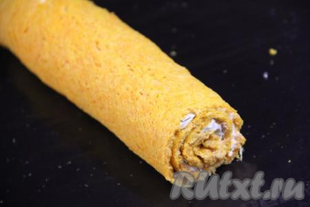 Затем свернуть морковный корж с сырной начинкой в плотный рулет, начиная с широкой стороны, и завернуть в фольгу. Убрать в холодильник на ночь.