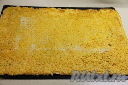 Достать морковный корж из духовки и слегка остудить. Затем аккуратно снять пергамент с коржа.