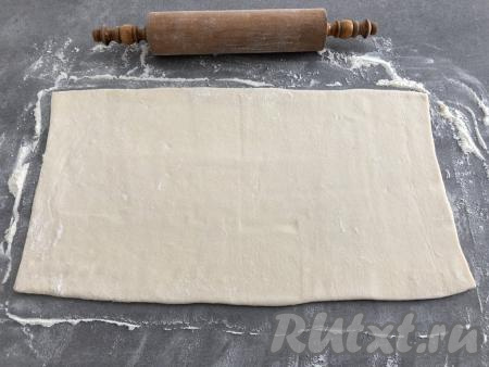 Рабочую поверхность слегка присыпать мукой, чтобы тесто не прилипало. Слоёное тесто немного раскатать (тонко раскатывать не нужно, чтобы слойки получились пышными).
