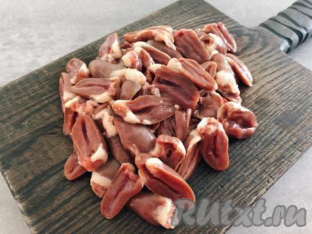 Куриные сердечки, если они заморожены, полностью размораживаем при комнатной температуре. Промываем сердечки водой. Разрезаем каждое сердечко на 2 половинки, убираем лишний жир и сгустки крови, промываем, даём немного обсохнуть, солим, перемешиваем.