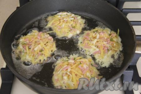 Хорошо разогреть растительное масло в сковороде, уменьшить огонь до среднего, а затем выкладывать по 1,5 столовых ложки теста из картошки, ветчины и сыра, формируя круглые драники. 