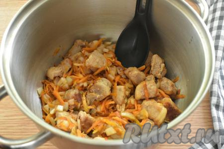 Обжаренные кусочки свинины с овощами со сковороды перекладываем в глубокую кастрюлю с толстым дном.