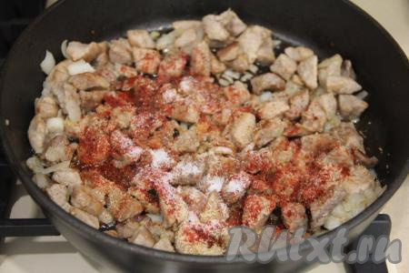 Затем посолить свинину с луком, всыпать специи по вкусу (у меня - паприка), перемешать.