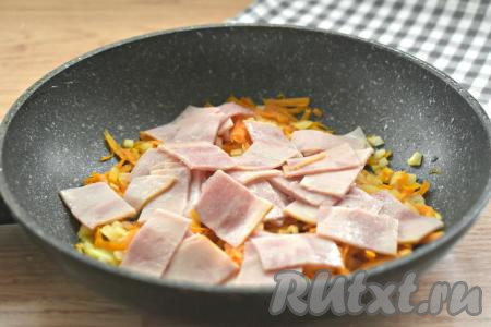 Колбасу (или ветчину) нарезаем на кусочки (или на кубики), выкладываем к обжаренным морковке с луком, перемешиваем, жарим 2 минуты, иногда помешивая.