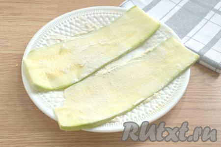 На плоскую большую тарелку насыпаем муку. Несколько полосок из кабачка обваливаем в муке с двух сторон. Покрываем мукой столько полосок, сколько одновременно в один слой можно выложить на сковороду, на которой вы будете обжаривать кабачки.