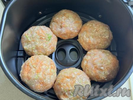 Влажными руками из каждой части фарша сформировать круглую котлету. Выложить котлеты из куриного фарша и кабачка на решётку аэрогриля. 