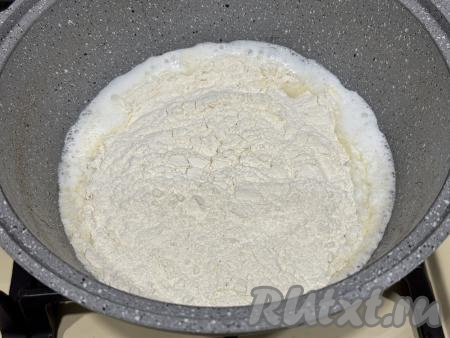 Немного уменьшить огонь, всыпать муку в кипящую смесь молока и масла. 