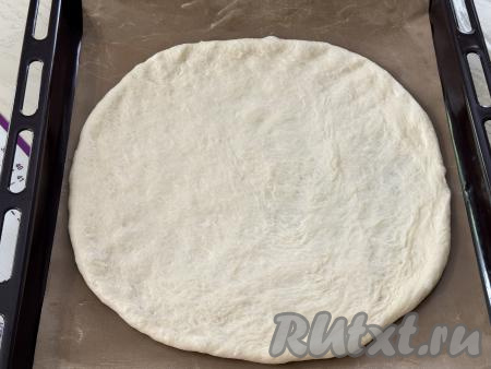 Раскатать большую часть теста на присыпанной мукой поверхности в круг диаметром 30 сантиметров. Выложить раскатанное тесто на противень, застеленный ковриком (или бумагой) для выпечки. 