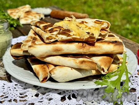 Готовые треугольники из лаваша с сыром переложить с решётки мангала на тарелку и сразу, с пылу с жару, подать к столу. Сочетание горячего тянущего сыра и приятно похрустывающего лаваша - это очень вкусно!