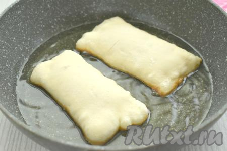 В сковороде хорошо разогреваем растительное масло. Выкладываем в горячее масло пирожки «швом» вниз. Масло должно доходить до середины пирожков. Жарим пирожки с яблоками до подрумянивания слоёного теста с двух сторон (ориентировочно по 2,5 минуты с каждой стороны).