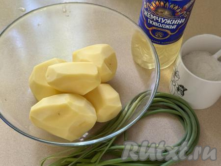 Подготовить продукты для приготовления жареной картошки с чесночными стрелками. Картошку очистить. Стрелки чеснока промыть водой. Отрезать соцветие, находящееся вверху каждой чесночной стрелки.