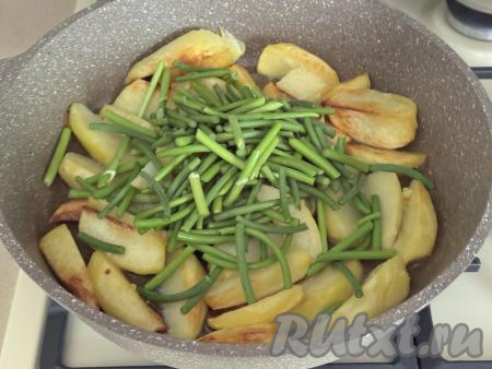 Пока жарится картошка, чесночные стрелки нарезать на кусочки длиной примерно 4 сантиметра. К картошке, обжаренной до полуготовности, добавить чесночные стрелки, перемешать, сразу посолить по вкусу. 