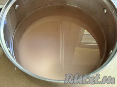 По прошествии 20 минут слить воду из банок в кастрюлю, добавить сахар и 1 литр воды, перемешать, поставить на сильный огонь, дать сиропу закипеть.