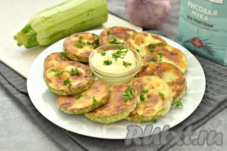 Кабачки, жареные в рисовой муке, с бумажных полотенец перекладываем на тарелку, посыпаем мелко нарезанной зеленью и, дополнив соусом (у меня - соус из майонеза и чеснока), подаём к столу. Кабачки получились вкусными, покрытыми аппетитной, мягкой корочкой снаружи, и нежными внутри.